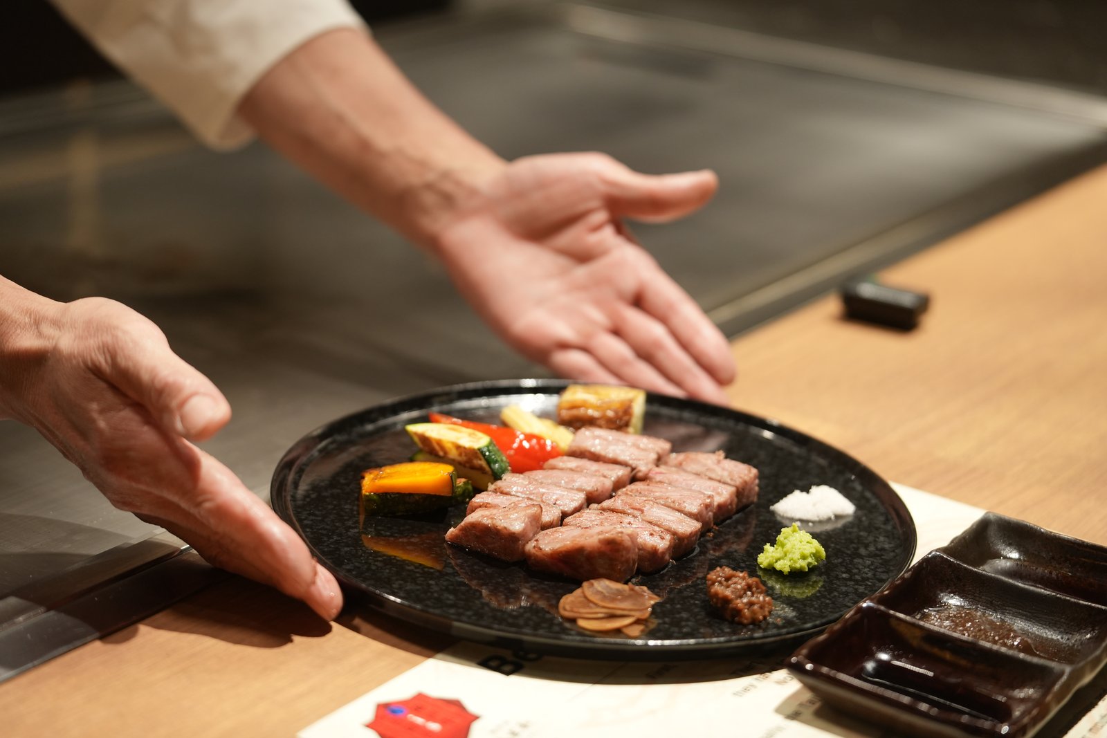 A chef presenting a freshly grilled Kobe beef steak to a guest