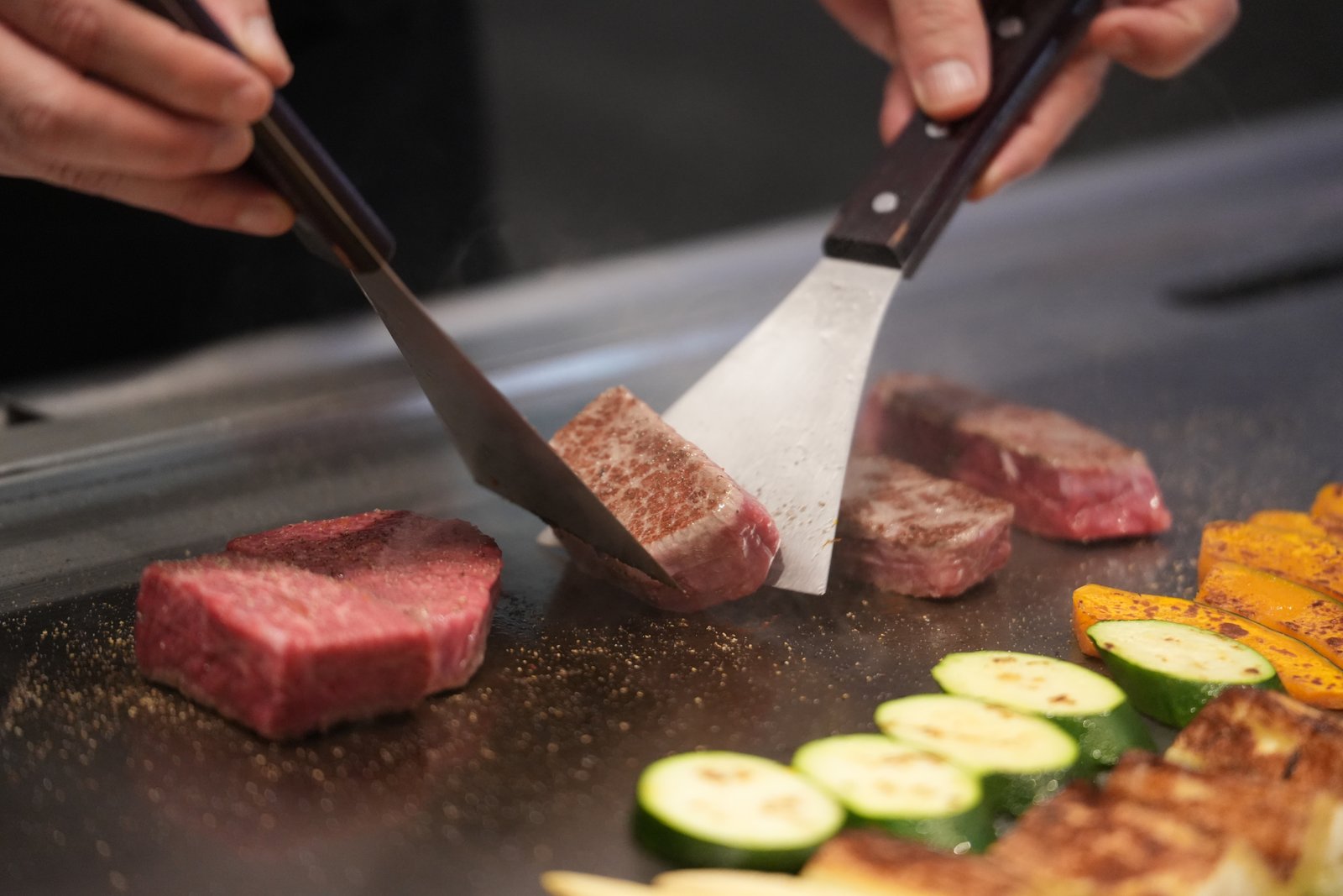 A chef grilling Kobe beef steak at the teppanyaki counter